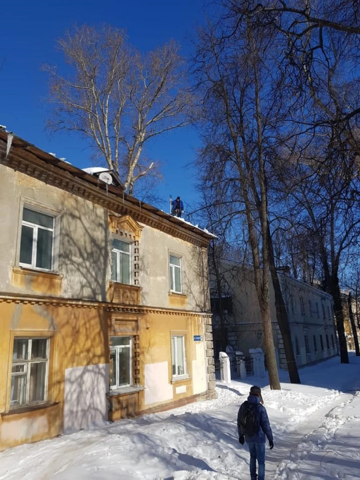 Покривите на куќите прочистуваат од icicles и снег во советското подрачје