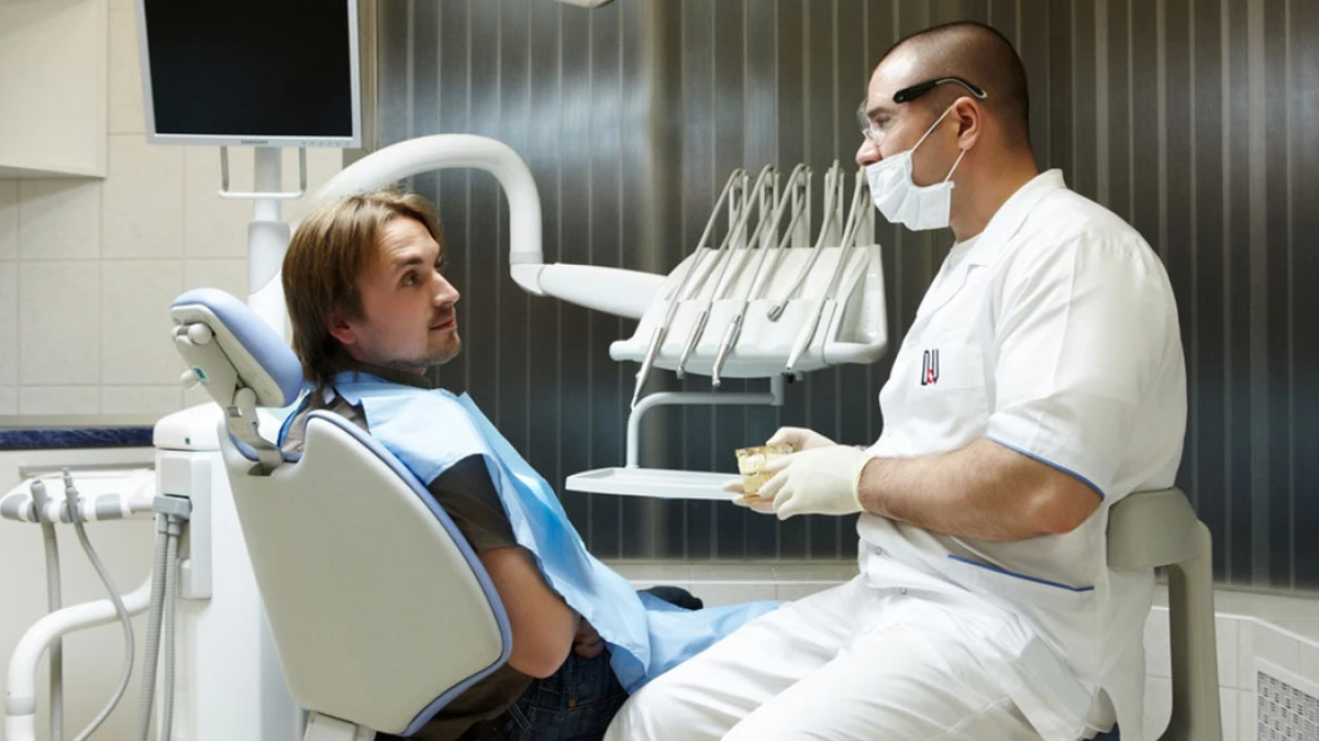 Врач занимающийся протезированием зубов. Стоматолог. Осмотр стоматолога. Зубной врач и пациент. Обследование больного у стоматолога.